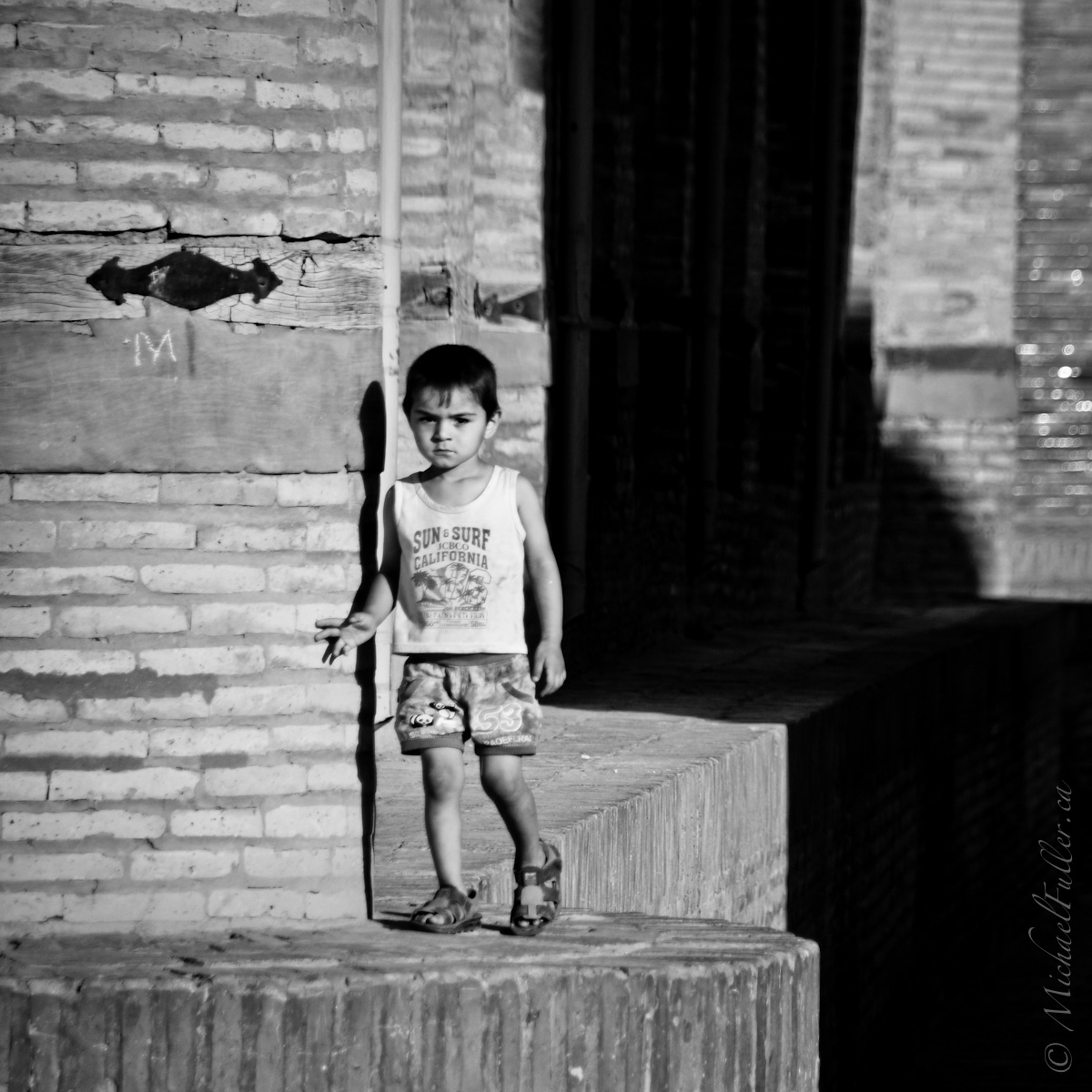 In the empty early morning streets, a child strolls aimlessly and unsupervised.
